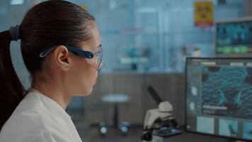 Biology specialist working with computer to examine dna animation in laboratory. Microbiologist with protective glasses using lab equipment to work on scientific experiment for innovation. video