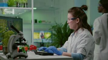 Chemist researcher analyzing test sample putting under microscope for pharmaceutical experiment. Scientist engineering researching for organic gmo plants while working in microbiology food laboratory video