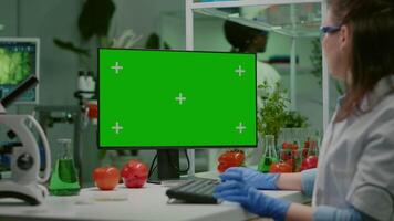 Scientist woman working on computer with mock up green screen chroma key with isolated display observing chemical test. Pharmaceutical researcher working in microbiology laboratory video