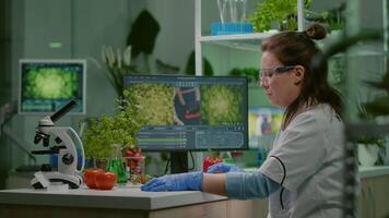 botânico investigador digitando médico perícia em computador enquanto analisando amostra folha para biológico experimentar. biólogo especialista examinando orgânico OGM teste enquanto trabalhando dentro botânica laboratório video