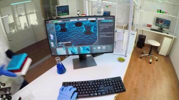 POV of researcher doctor typing at computer, analysing DNA scan image, while coworker bringing him samples of blood. Group of biochemistry scientists examining virus evolution using high tech video