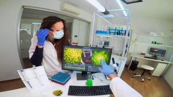 POV of laboratory medical stuff disscussing about vaccine development holding chemical container with green sample. Scientist working with DNA scan image in modern equipped laboratory using high tech video