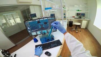 FPV of biologist doctor checking liquide from test tubes, writing on pc, while colleague bringing blood samples. Scientists examining vaccine evolution in medical lab using high tech for research. video