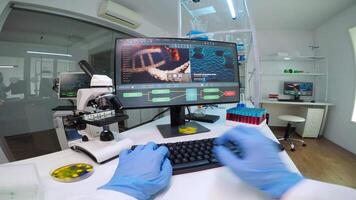 POV of man biologist checking DNA information typing on pc in modern equipped laboratory. Scientists examining vaccine evolution in medical lab using high tech, chemistry tools for scientific research video