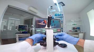 POV of scientists working in lab with patri dish looking into microscope blood analysis. Medical stuff examining vaccine development using high tech researching treatment against covid19 virus video