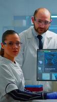 Vertical . Team of scientists sitting in laboratory looking at camera in modern equipped lab. Group of doctors examining virus evolution using high tech for scientific research, vaccine development. video