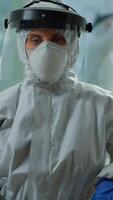 Vertical . Tired microbiologist in coverall sitting in laboratory looking at camera. Team of scientits examining virus evolution using high tech and chemistry tools for scientific research, vaccine development. video