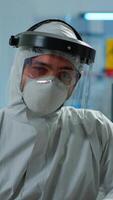 Vertical . Close up of tired chemist man doctor in coverall working in scientific equipped laboratory. Scientist working with various bacteria, tissue and blood samples, pharmaceutical research for antibiotics video