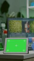 Vertical . Chemist researcher typing microbiology expertise on computer while in front standing on table tablet with mock up green screen chroma key with isolated display. Biologist working in medical lab video