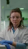 Vertical . Pov of biologist researcher woman with medical equipment analyzing with biologits team during online videocall meeting while sitting in botanic scientific lab. Specialists researching genetic mutation video