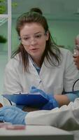Vertical . Two collegues checking sample of vegan meat writing biotechnology expertise after chemistry experiment. Scientists working on plant-blased beef substitute in biology laboratory video