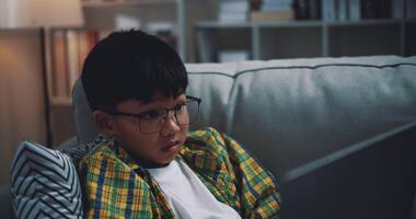 Dolly shot, Asian boy wearing glasses schoolboy using a laptop computer while sitting on the couch at home. Education, e-learning and lifestyle concepts. video