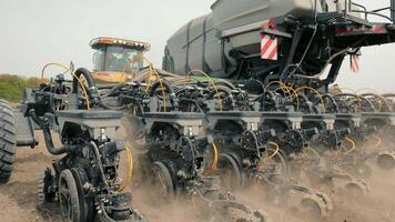 Modern Seeder in Action on Farmland, A close-up view of a modern seeder at work, planting seeds in a tilled field. The machinery is detailed with complex components, video