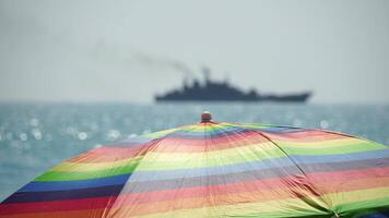 Rainbow colored beach umbrellas or parasols against blue sea during a sunny day on a beach. Symbol of vacations, relax, summer. Colorful umbrellas from the sun stand on the beach. Slow motion. video