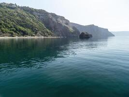 Aerial panoramic view of seascape with crystal clear azure sea and rocky shores. Yachts in a beautiful lagoon on backdrop of rocks. The concept of an ideal destination for summer travel and vacation. photo