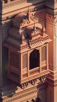 A stunning photograph of an intricately carved jharokha, an ornate window design often seen in Indian palaces. The jharoka is adorned with intricate floral and geometric patterns. photo