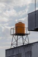 yellow plastic water tank tower on the roof with a clear sky in the background photo