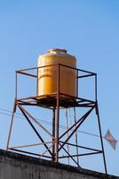 yellow plastic water tank tower on the roof with a clear sky in the background photo