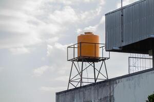 yellow plastic water tank tower on the roof with a clear sky in the background photo