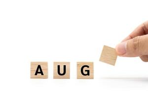 Hand place wooden blocks with AUG text isolated on white background. August and Calendar concept. Copy space. photo