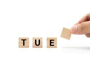 Hand place wooden blocks with TUE text isolated on white background. Tuesday and Calendar concept. Copy space. photo