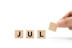 Hand place wooden blocks with JUL text isolated on white background. July and Calendar concept. Copy space. photo