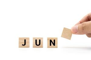 Hand place wooden blocks with JUN text isolated on white background. JUNE and Calendar concept. Copy space. photo