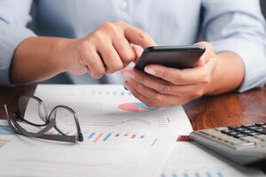 Close-up of hand holding a smartphone with the chart, graph report for the business. Space for text. Business, finance, planning, and communication concept photo