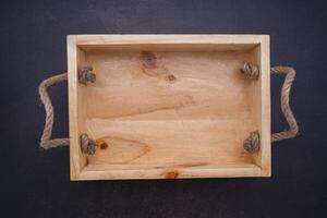 An empty wooden box is placed on dark stone background. Wood design. Space for text. Top view photo