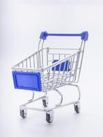 Mini shopping cart with a blue handle on white background. High angle of view. Space for text. Concept of shopping and e-commerce photo