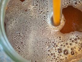 Close-up of craft beer and foam in a fermentation container. Process of making home beer from malt. Craft beer from barley and dark malt photo