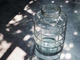 A large glass bucket, without a lid, is placed on a floor in a home with sunlight photo
