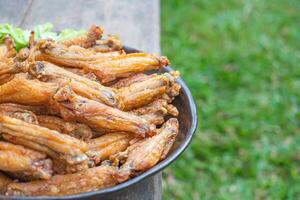 Fried chicken wings with fish sauce with salad vegetables on a white plate placed on a wooden table. Close-up photo. Space for text. Concept of foods photo