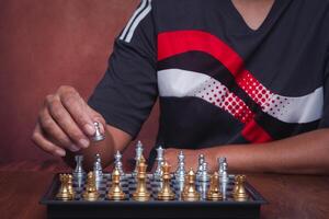 The midsection of playing a game of chess on the chessboard while sitting indoor. The decision on the game. Concept of strategy and planning photo