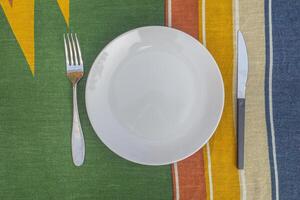 Top view of a plate, fork, knife on the dinner table in the garden. Space for text. Close-up photo