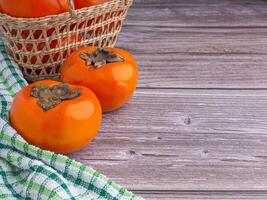 Side view of persimmons with cloth on a wooden table with copy space for text. Concept of health fruit photo