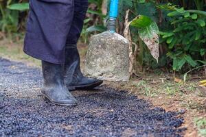 Man holding a cement rod for hammering to adjust the asphalt surface for the walkway. Close-up photo. Constructed from asphalt. Space for text photo