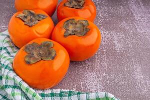 Top view of persimmons with cloth on a gray stone background with copy space for text. Concept of healthy fruit photo