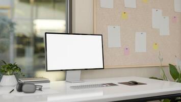 A computer desk in a modern office, a computer with a white-screen mockup on the desk. photo