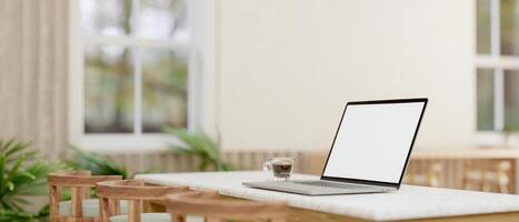 A laptop computer with a white-screen mockup on a table in a comfortable minimalist cafe. photo