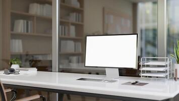 A computer desk in a modern office features a computer with white-screen mockup and office supplies. photo