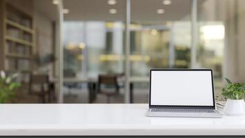 A laptop computer on a white tabletop with a blurred background of a meeting room. photo