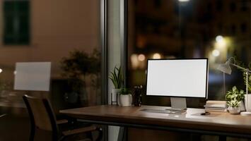 Contemporary private office at night features a computer with a white-screen mockup and a dim light. photo