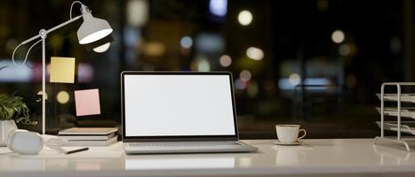 A laptop computer and accessories on a table against the window with a night city view. photo