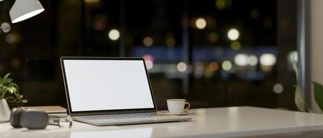 A laptop computer and accessories on a table against the window with a night city view. photo