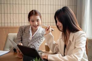 Two Asian businesswomen are discussing work on their digital tablets, having an informal meeting. photo