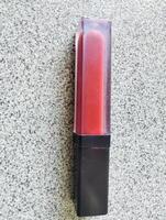 Red lip cream liquid lipstick and applicator, top view of creamy red lip cream with an elongated tube container photo