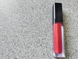 Red lip cream liquid lipstick and applicator, top view of creamy red lip cream with an elongated tube container photo