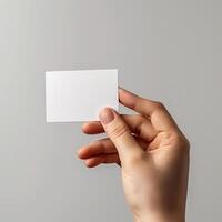 Hand holding a blank white business card against a plain background, ideal for branding and marketing purposes. photo