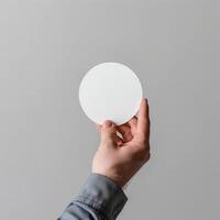 Man holding a white circular object against a gray background. Ideal for design, minimalism, and creative concepts. photo